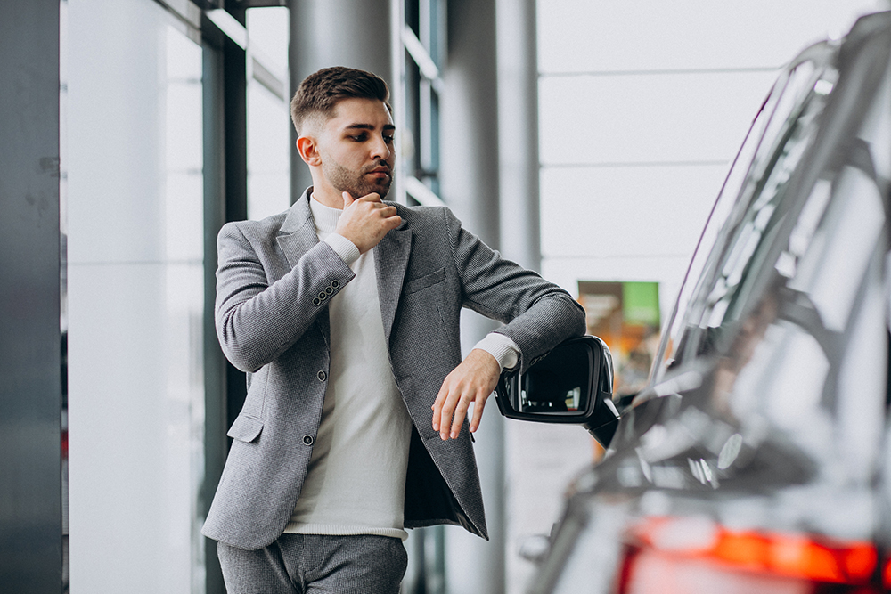 Handsome business man choosing a car in a car showroom Handsome business man choosing a car in a car showroom